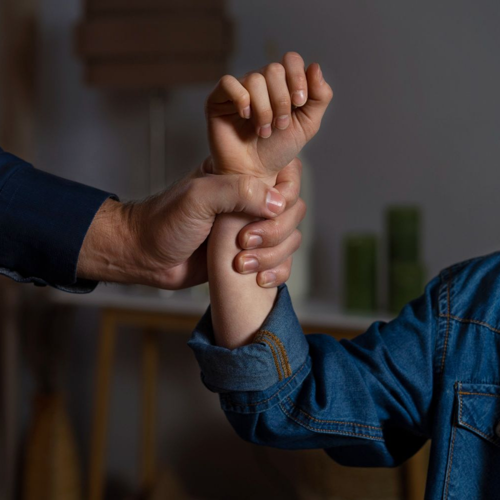 Adult hand gripping a child's arm. The child wears a denim jacket indoors. Domestic Assault in Nashville, Tennessee