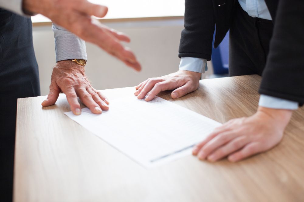 Two people examining a document on a wooden table, one gesturing with their hand. Boundary Disputes in Nashville, Tennessee