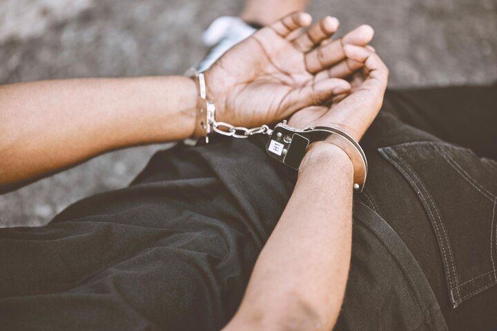 Person's wrists handcuffed, lying on a surface, wearing a black shirt and jeans. Resisting Arrest in Nashville, Tennessee