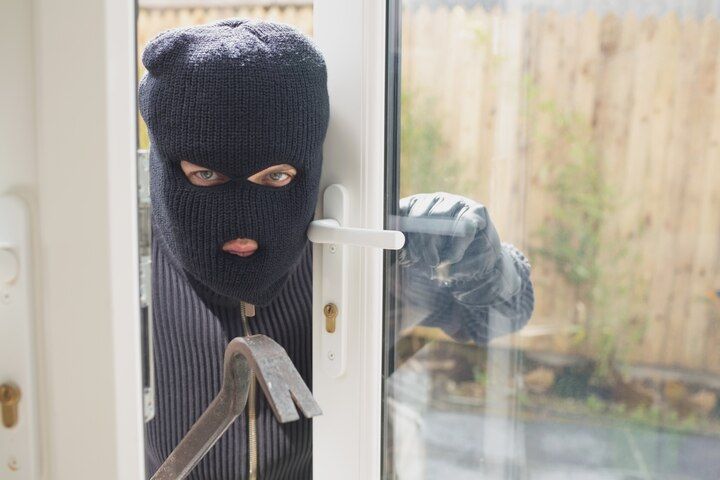 Person in a black ski mask using a crowbar to open a glass door. Aggravated Burglary in Nashville Tennessee