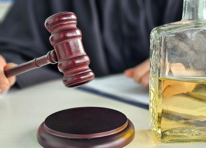 Judge with gavel and alcohol bottle on table. Public Intoxication in Nashville, Tennessee