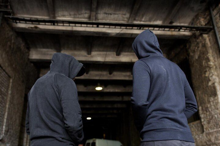 Two people in dark hoodies stand under an archway, backs to the camera, looking into a dim space. Aggravated Criminal Trespass in Nashville, Tennessee