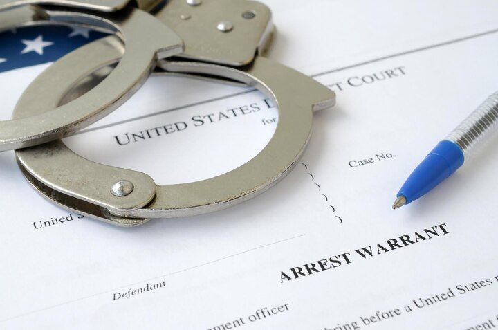Handcuffs on top of an arrest warrant form with a pen. OP Violations in Nashville, Tennessee