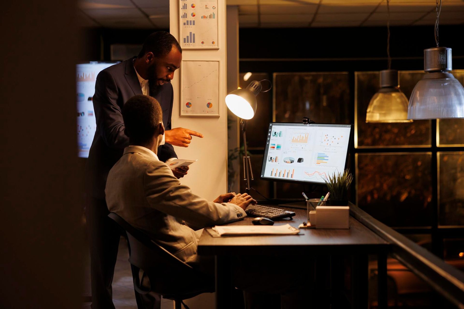 Two people reviewing computer screen data in dimly lit office. One points while the other types. Criminal Simulation in Nashville, Tennessee