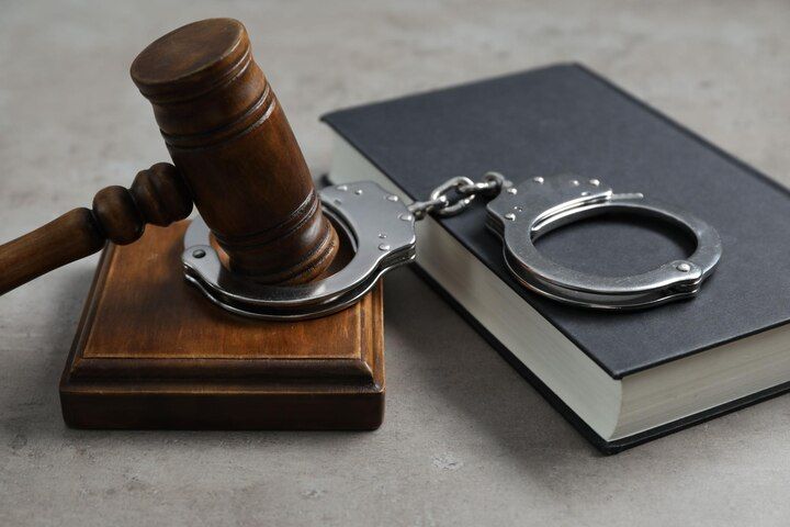 Wooden gavel and handcuffs rest on a closed book, symbolizing law and order. Criminal Impersonation in Nashville, Tennessee