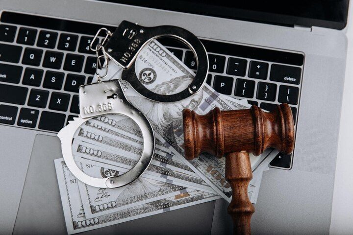 Handcuffs, cash, and gavel on a laptop keyboard, suggesting cybercrime and legal issues. Fraud in Nashville, Tennessee