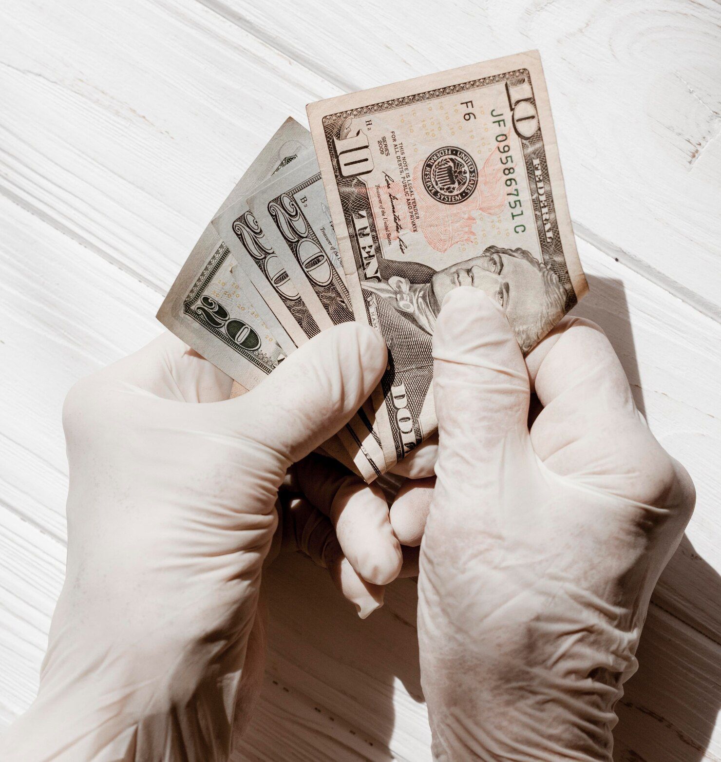 Hands in white gloves holding and counting U.S. dollar bills. Money Laundering in Nashville, Tennessee