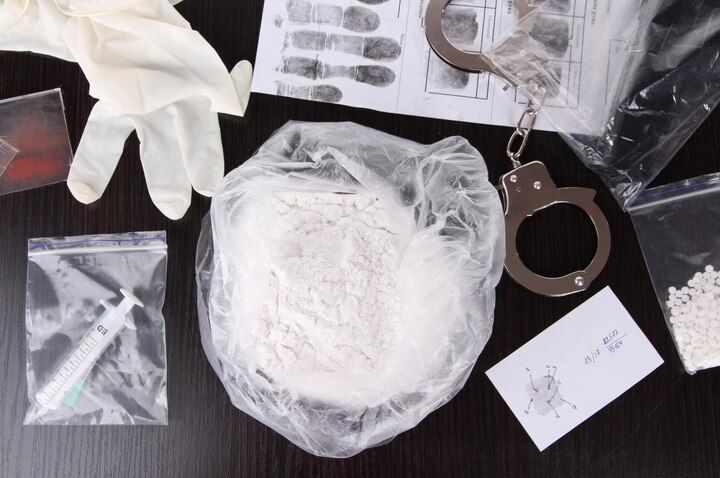 Evidence: bag of powder, syringe, handcuffs, fingerprints, gloves, small bags on a table. Drug Manufacturing in Nashville, Tennessee
