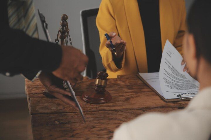 Lawyers at a wooden desk with a gavel, legal documents, and a client signing papers. Disorderly Conduct in Nashville, Tennessee