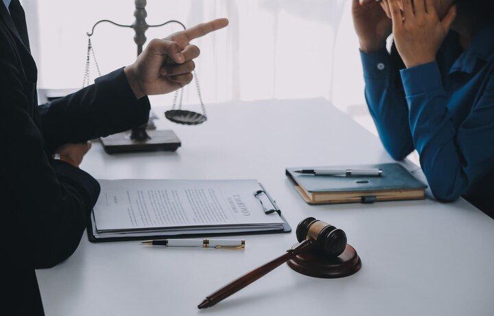 Lawyer points at document. Person with head in hands at a table, gavel, and scales of justice. Disorderly Conduct in Nashville, Tennessee
