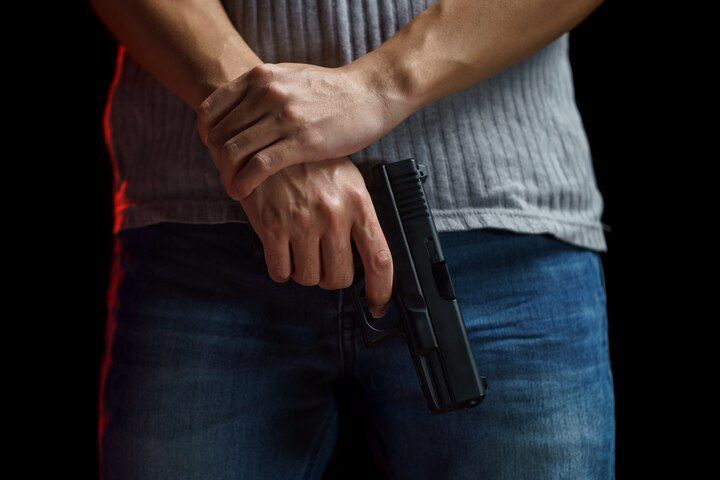Person holding a handgun in front, against a black background. Firearm During Dangerous Felony in Nashville, Tennessee