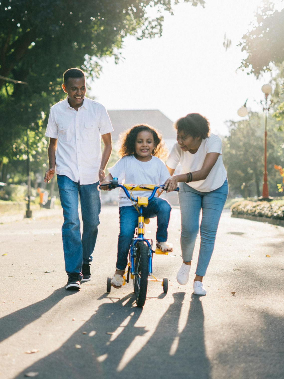 Family helps a child ride a bicycle on a sunny path. Practice Areas in Nashville, Tennessee