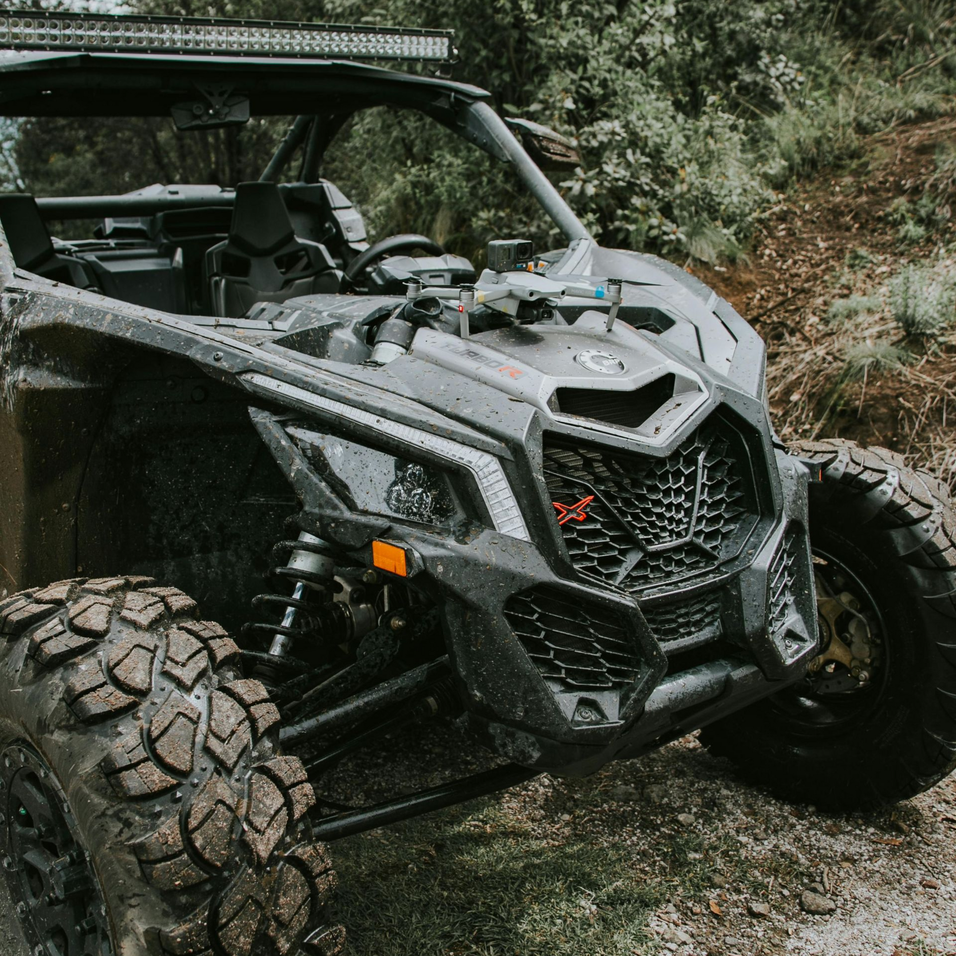 Black off-road vehicle with mud-covered tires parked on a dirt path in a wooded area. ATVAccidents in Nashville, Tennessee
