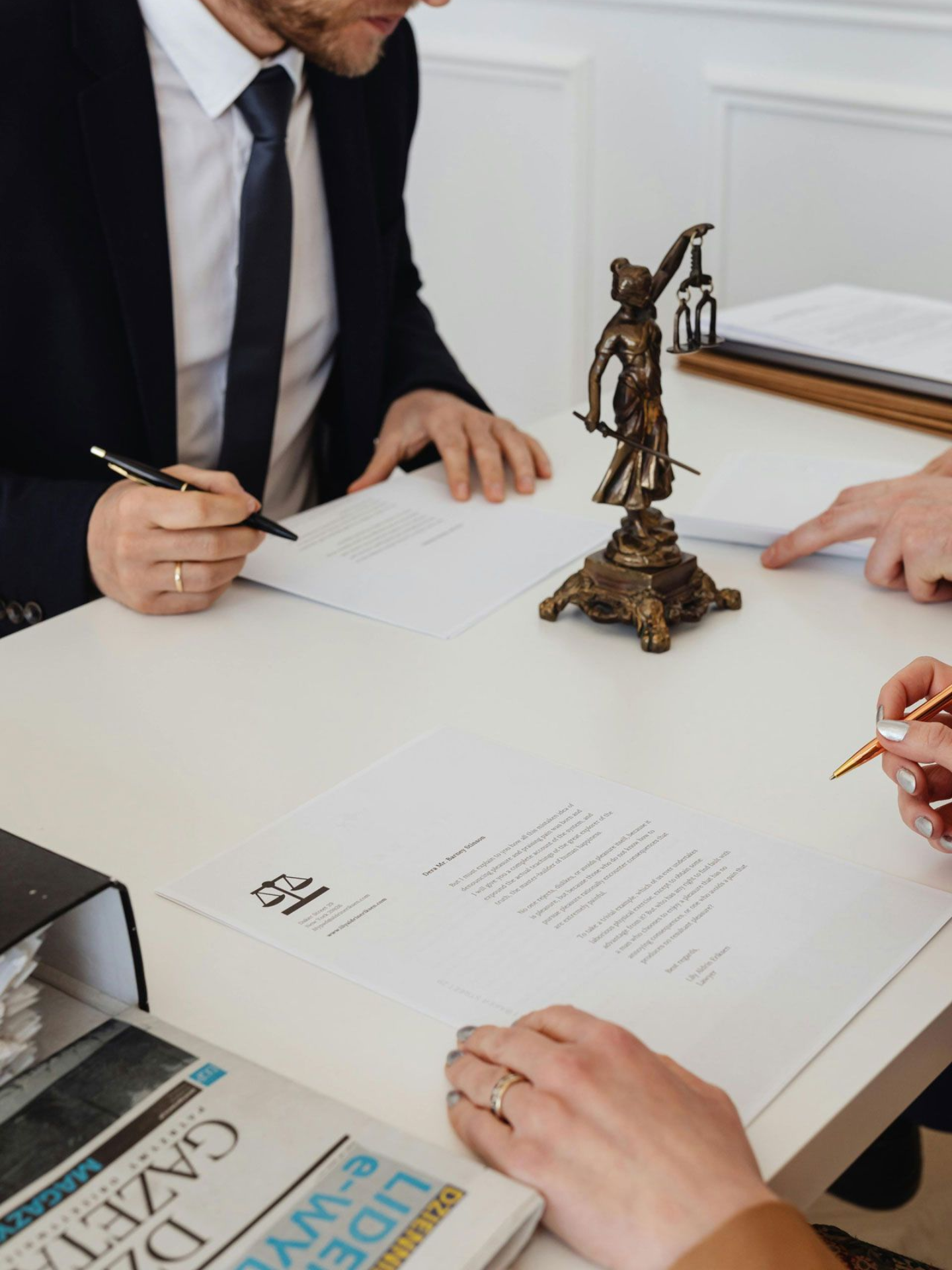 People at a table, signing documents. Legal setting with a statue and papers. Practice Areas in Nashville, Tennessee