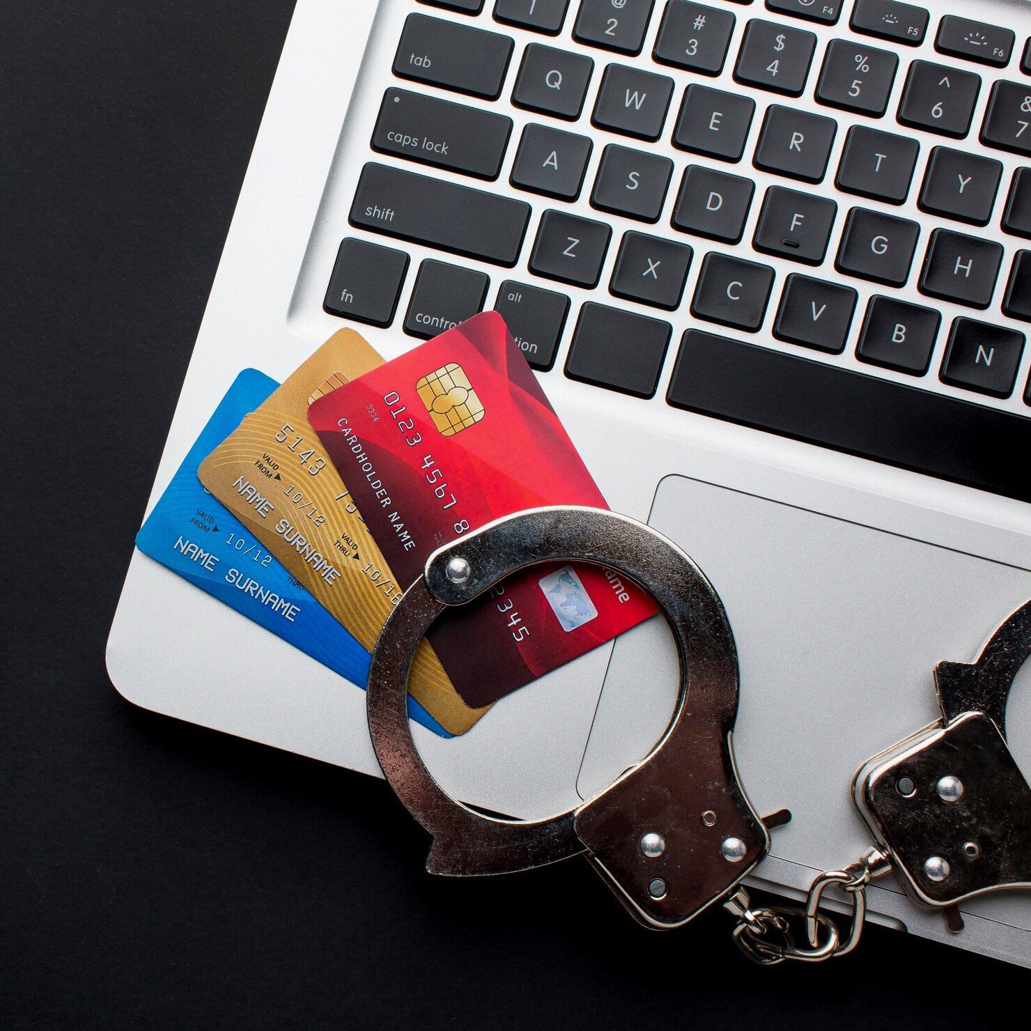 Credit cards and handcuffs on a laptop keyboard, representing financial crime. Credit / Debit Card Fraud in Nashville, Tennessee