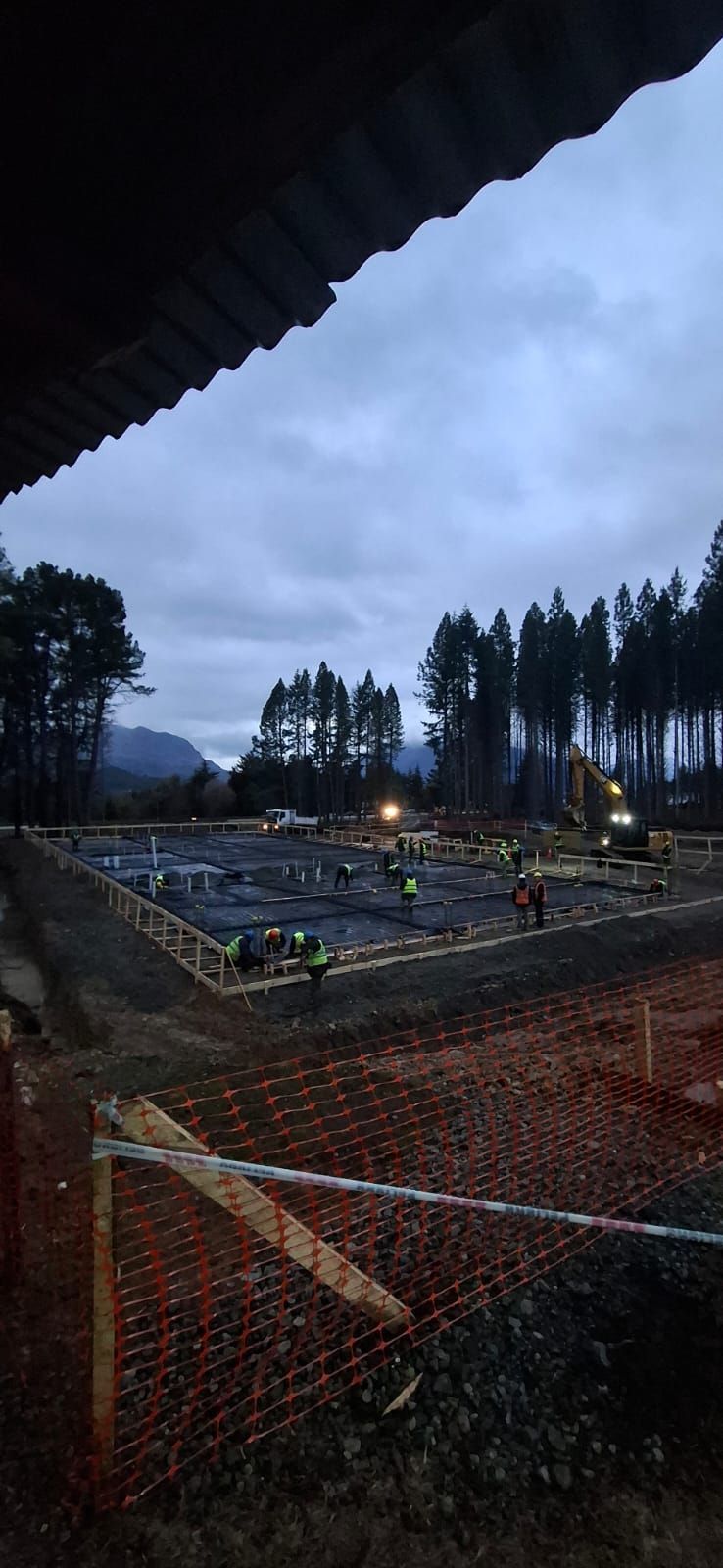 Grúas de construcción amarillas y maquinaria pesada en una concurrida obra en un día despejado.