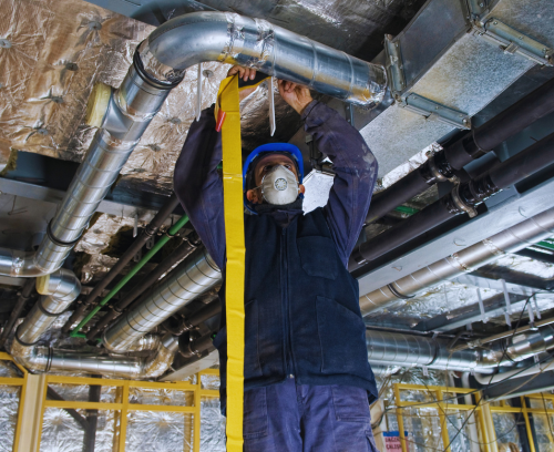 A man is measuring a pipe with a tape measure