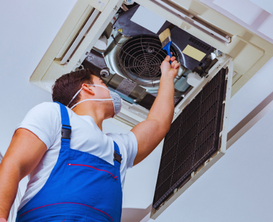 A man wearing a mask is working on an air conditioner.
