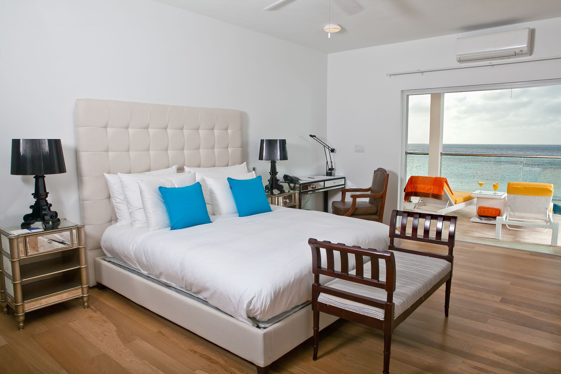 Bedroom with a large bed, ocean view, wooden floor, and a small patio.