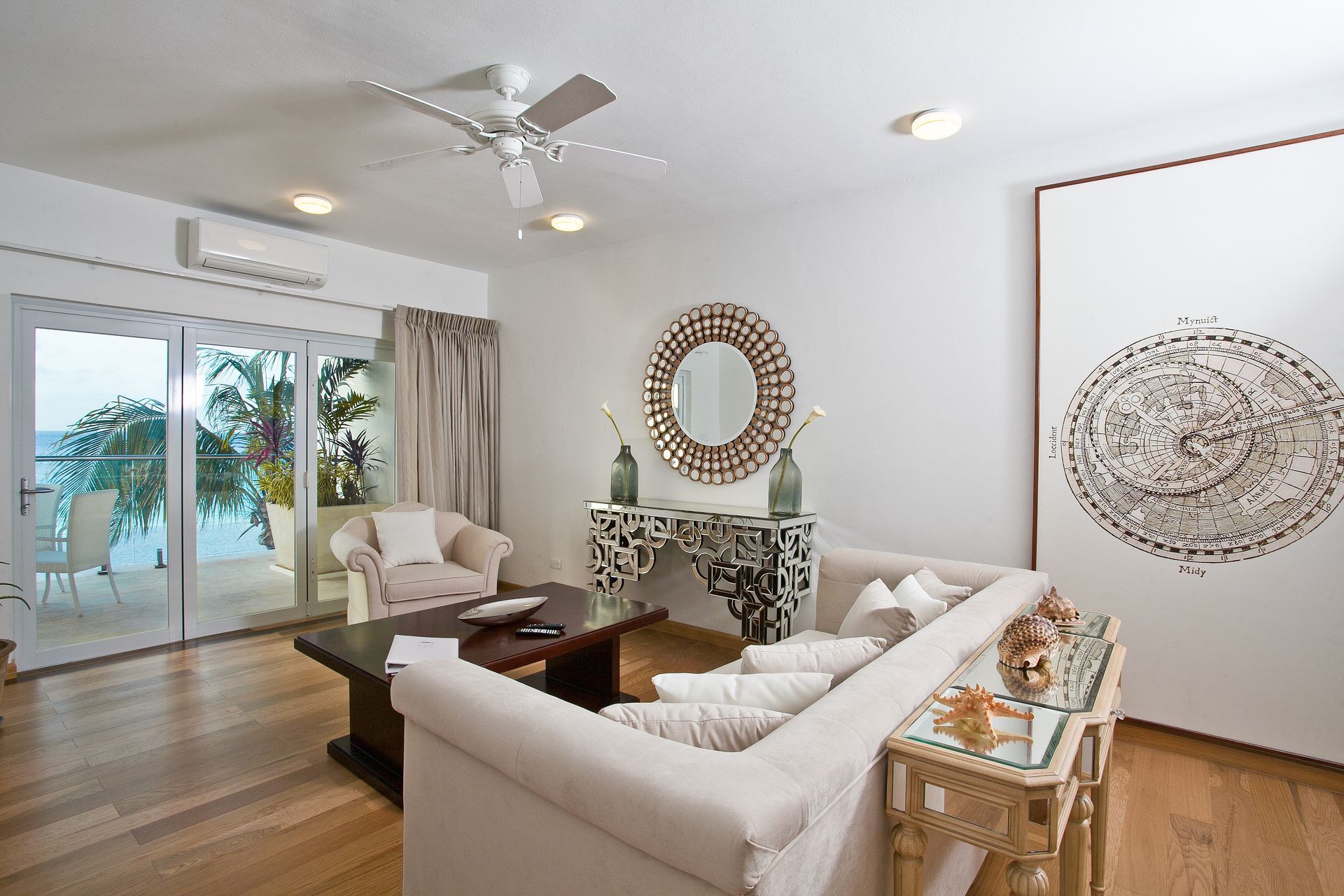 Living room with light wood floors, white sofa, and view of water through glass doors.