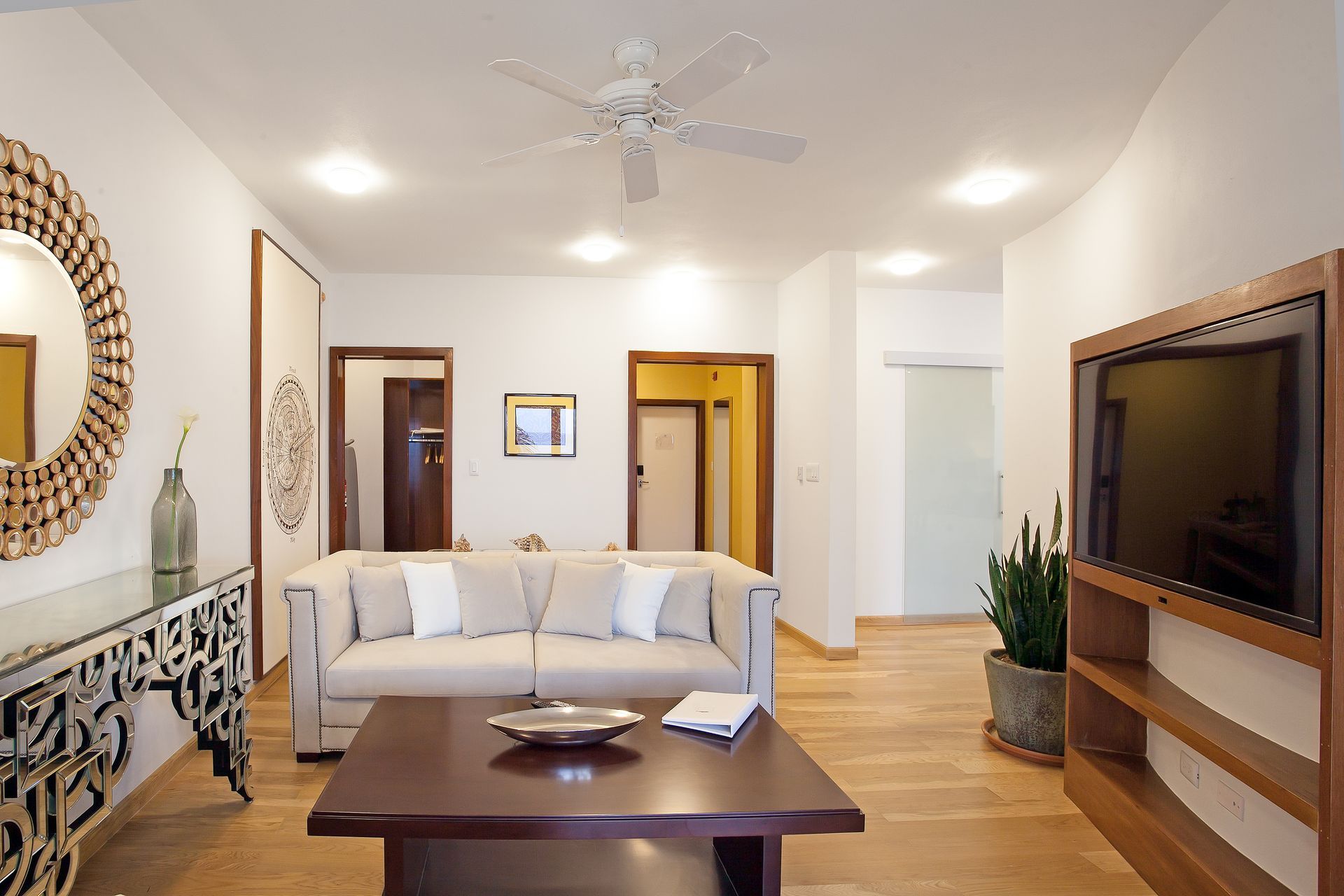 Living room with beige sofa, wooden floors, and large TV.