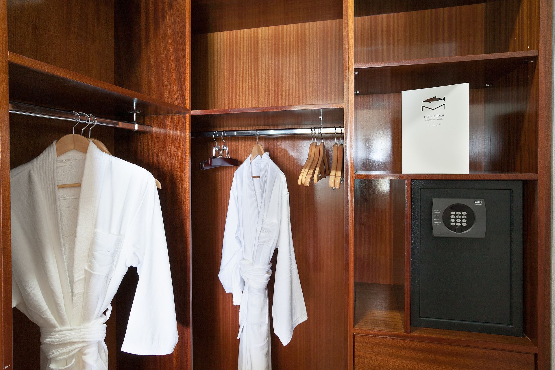 Wooden closet with white bathrobes, a safe, and a notepad.