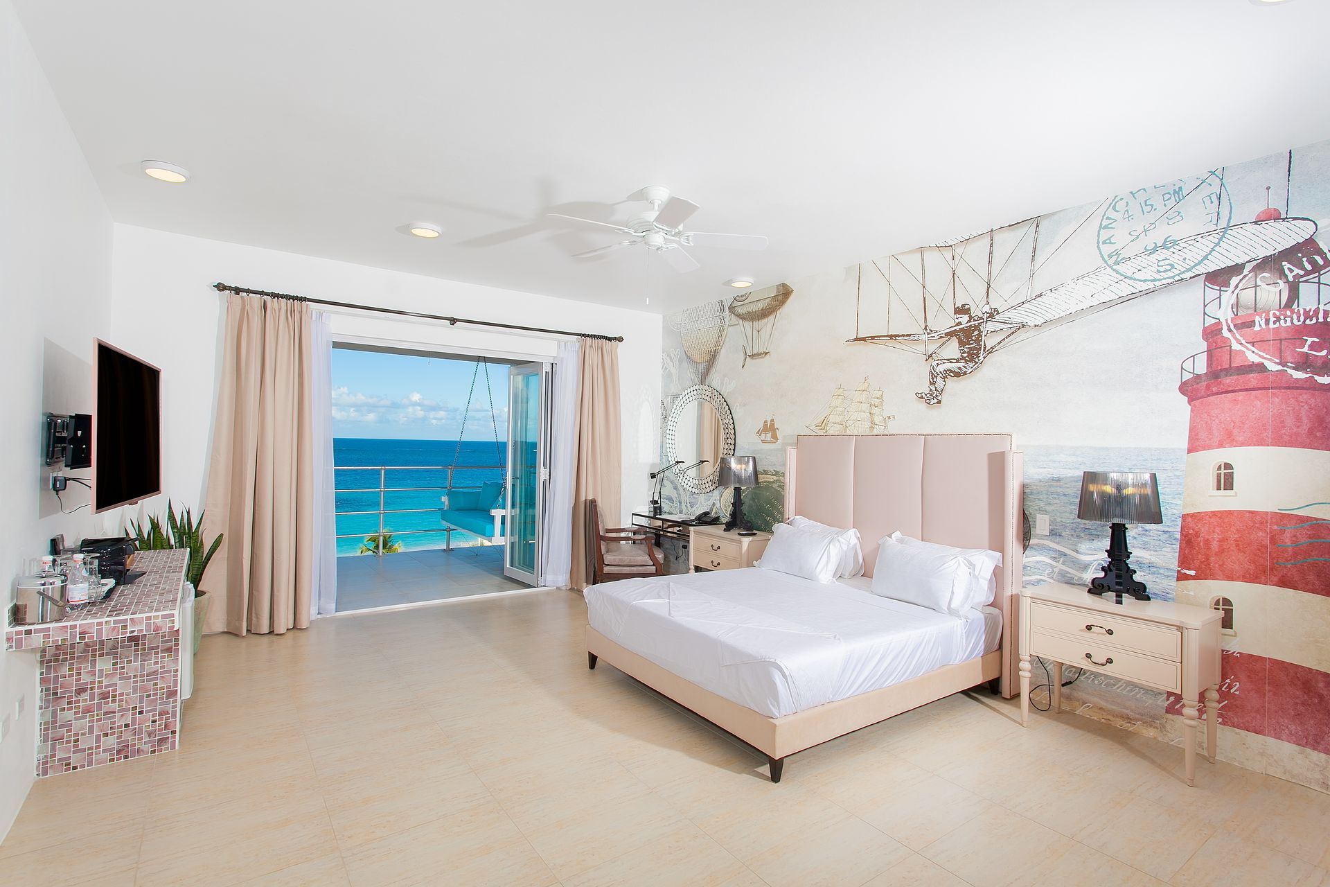 Bedroom with ocean view, large bed, lighthouse mural, and balcony.