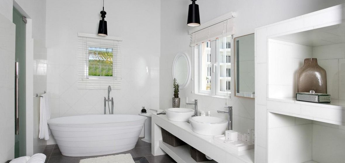White modern bathroom with a freestanding tub, double sinks, and open shelving.