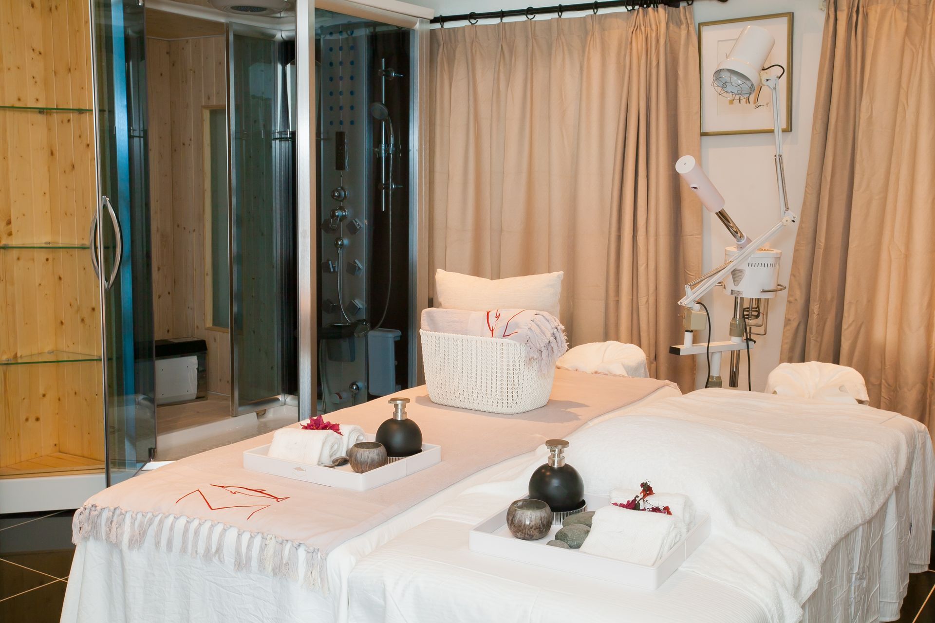 Spa room with massage beds, towels, aromatherapy items, and a shower.