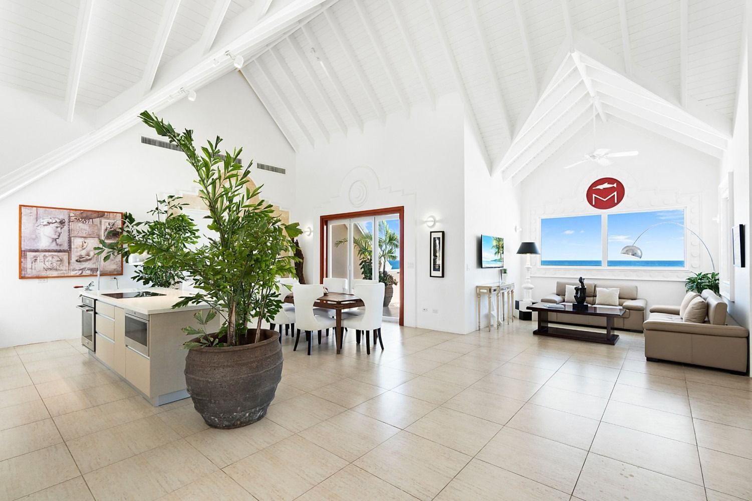 Bright, open-plan living space with white walls, vaulted ceiling, and large windows overlooking the ocean.