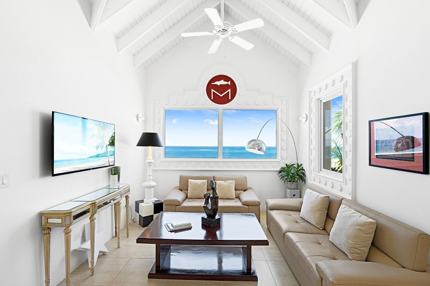Bright, modern living room with ocean view; beige couches, dark wood coffee table, and white walls.