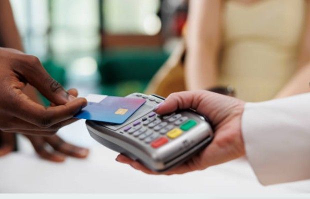 A person paying with their phone on a payment terminal at a cafe.
