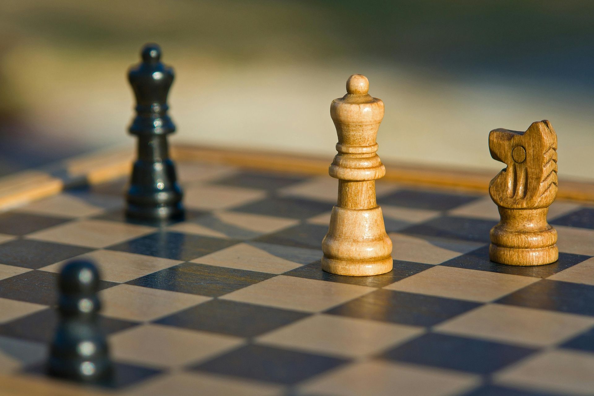 Chessboard with black queen, pawn, and a knight facing a white king.