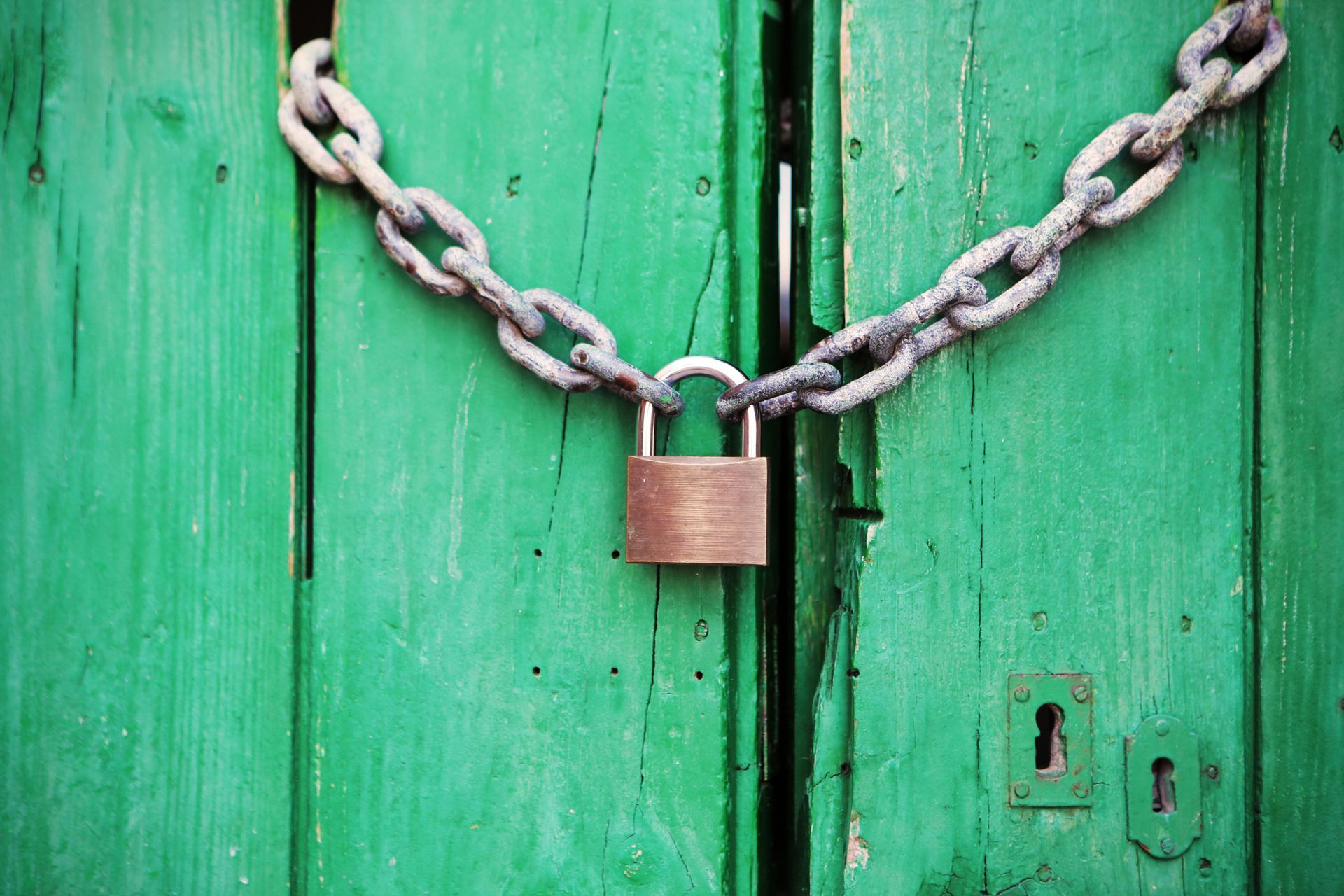 Green wooden door with chain and padlock.