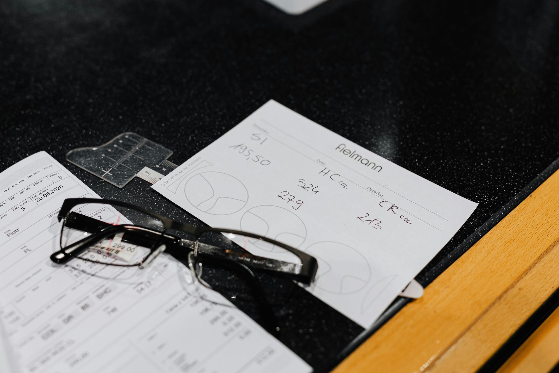 Doctor on phone, writing notes. He has grey hair, beard, glasses, a stethoscope, and is wearing a white coat.