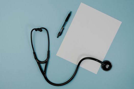 Stethoscope, pen, and blank paper on a light blue surface, suggesting healthcare and medical documentation.
