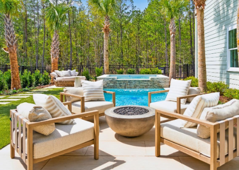 Outdoor seating area with pool, fire pit, and palm trees in a sunny setting.