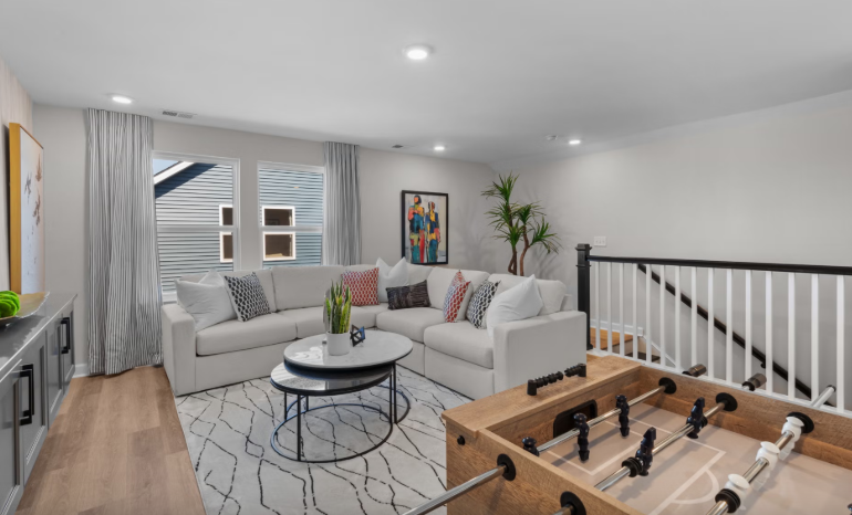 Cozy living room with white sectional, foosball table, and neutral decor.
