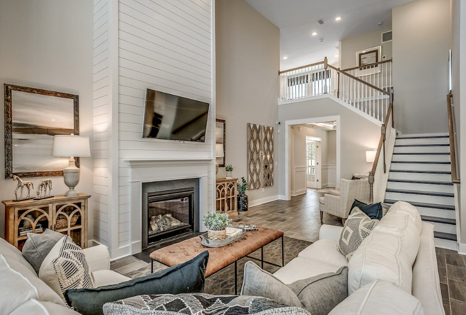 Living room with fireplace, white couches, staircase, and open layout.