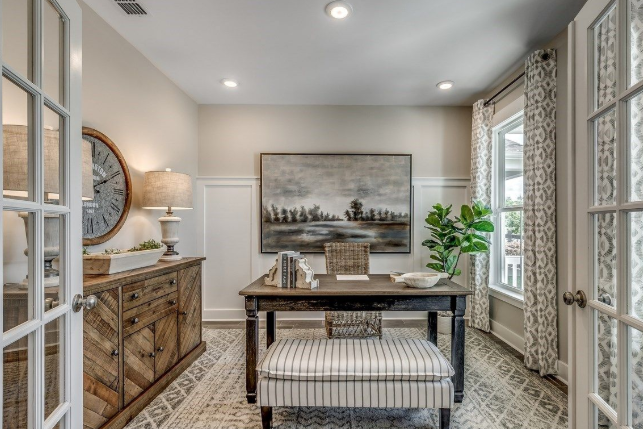 Office with desk, striped bench, rustic cabinet, landscape art, and French doors.