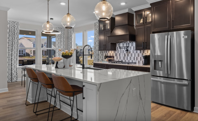 Modern kitchen with island, dark cabinets, stainless steel appliances, and pendant lights.
