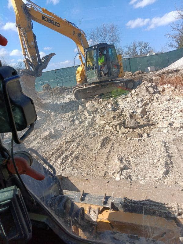 A yellow excavator is moving dirt and rocks on a construction site.