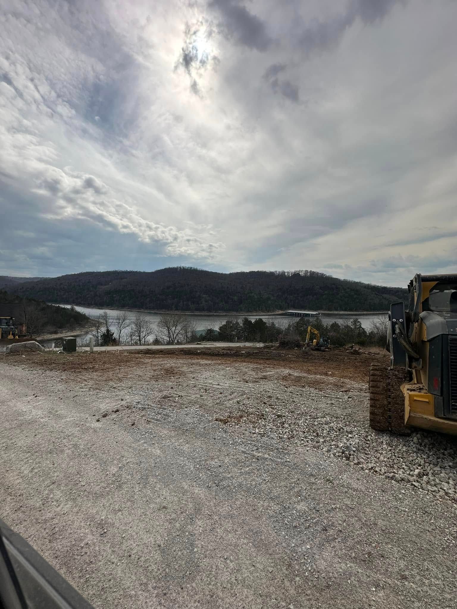 A bulldozer is parked in a gravel lot with mountains in the background.