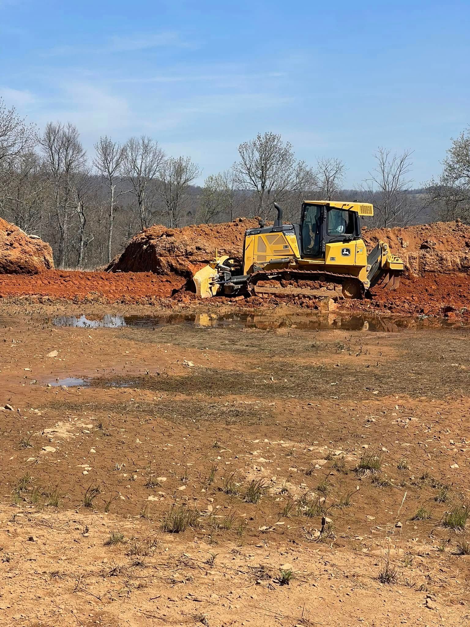A bulldozer is moving dirt in a muddy field.
