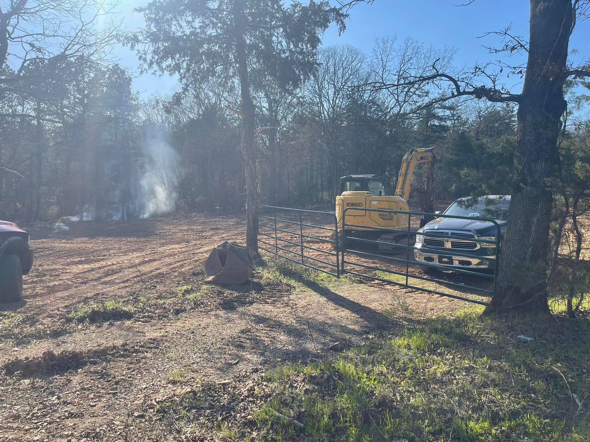 A truck is parked in a dirt field next to a bulldozer.