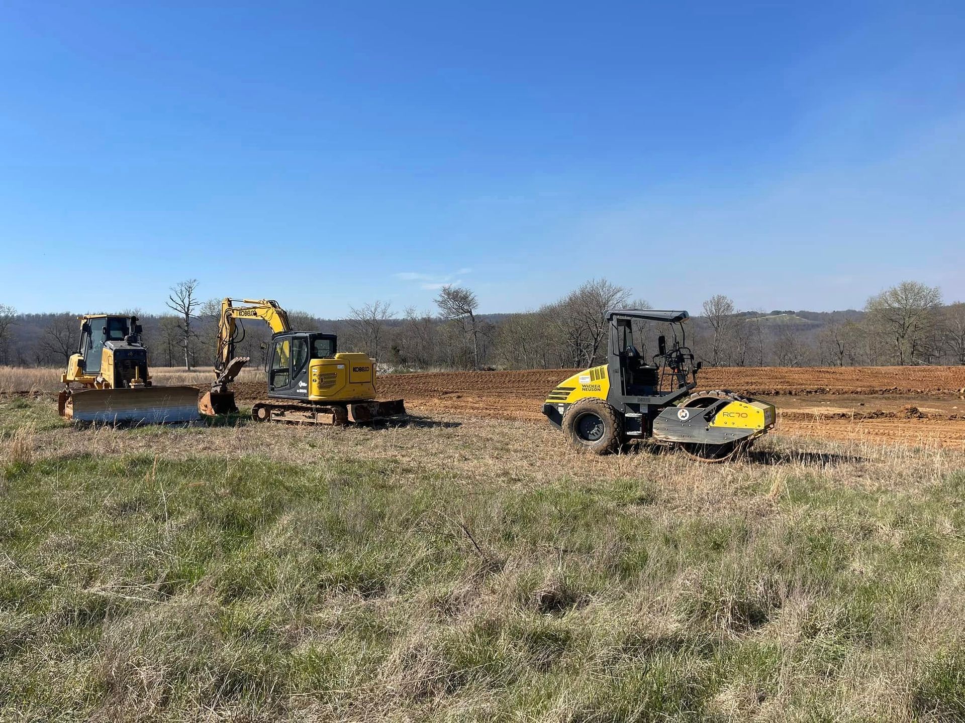 A group of construction vehicles are sitting in a field.