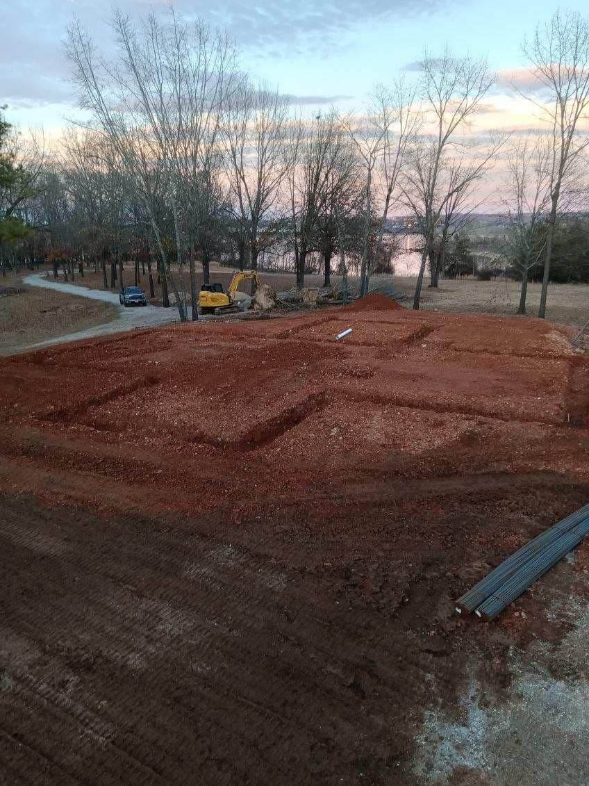 A construction site with a lot of dirt and trees in the background.
