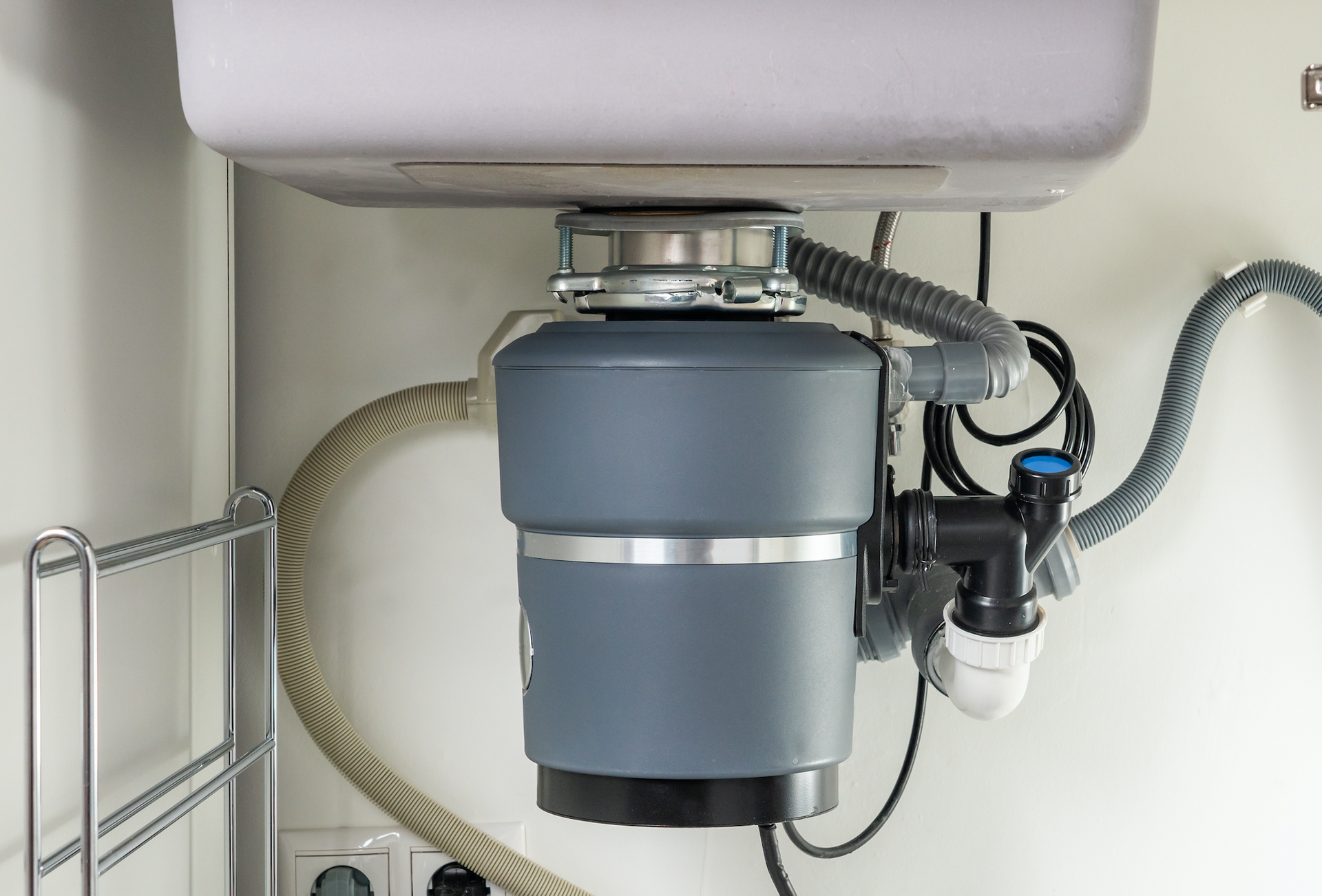 A garbage disposal is under a sink in a kitchen.