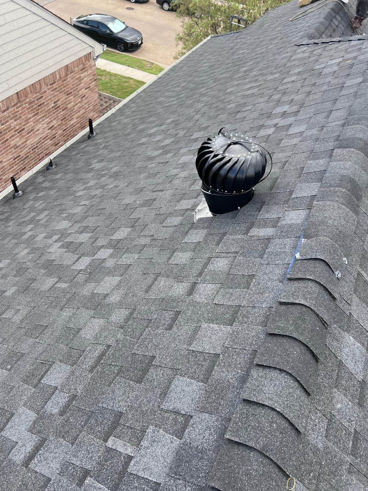 Dark asphalt shingle roof with a rotating turbine vent.