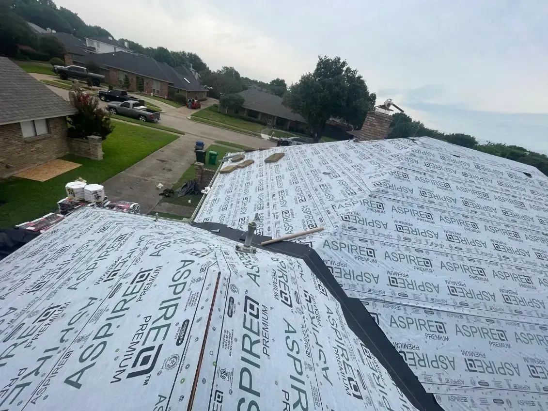 Roof partially covered with Aspire underlayment; houses and a street are in the background.